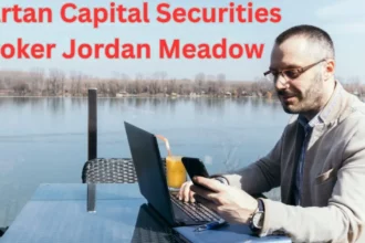 a person sitting at a table with a laptop and a phone spartan capital securities broker jordan meadow